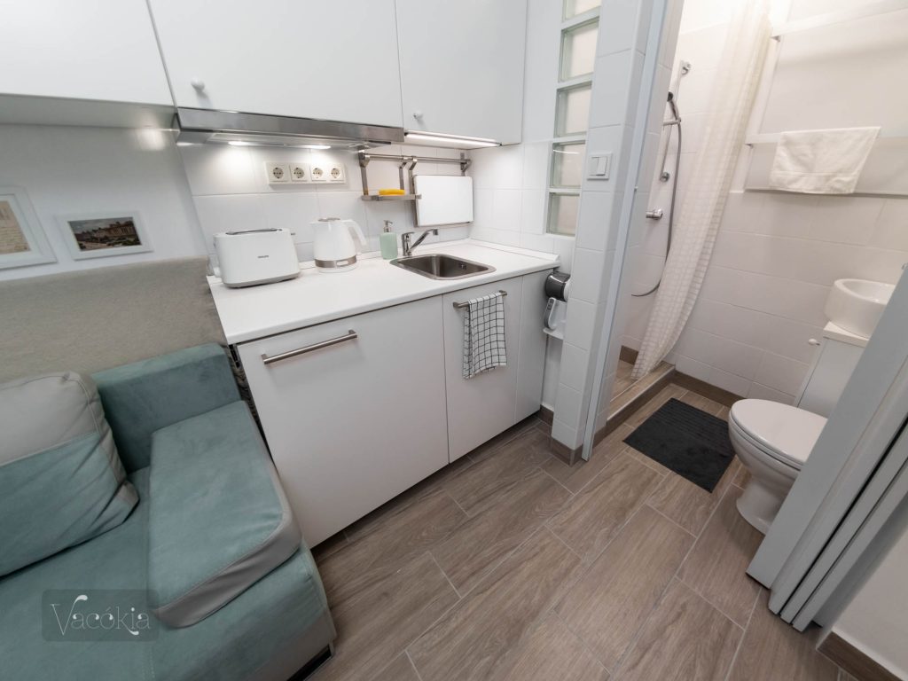 A teakonyha jól felszerelt: kivezetett páraelszívó, eltehető indukciós főzőlap, grilles mikró, kenyérpirító, vízforraló, french press, edények stb. A sarokba egy miniporszívót tettünk, dokkolóval együtt.